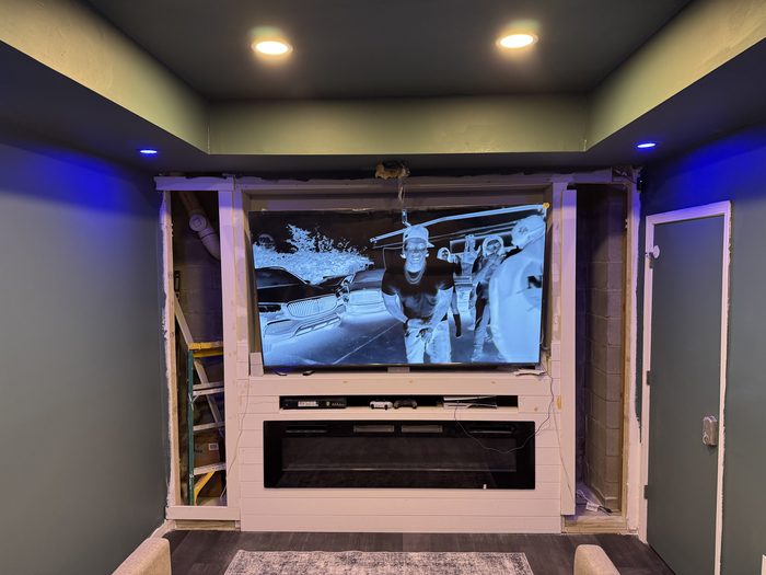 Basement media wall with a recessed TV, an electric fireplace and blue accent lighting
