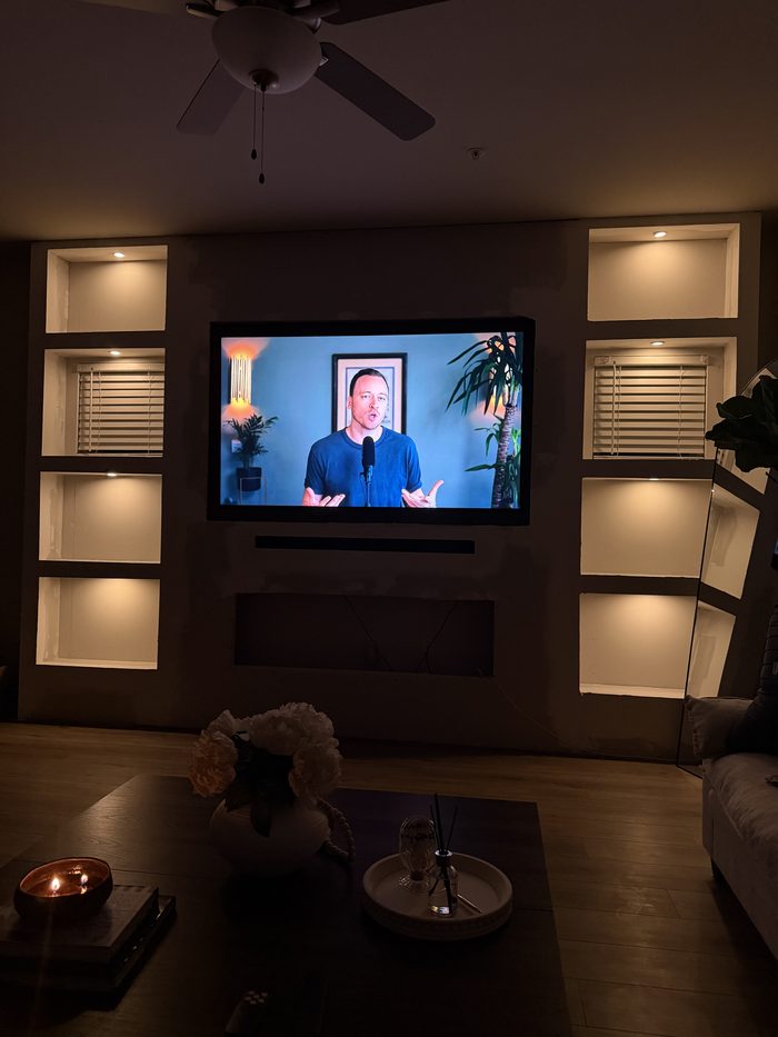 Built-in TV wall with lit niches and shelves on both sides
